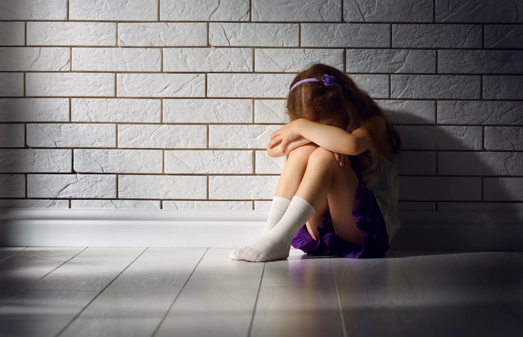 Enfant assis contre un mur